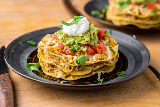 Crunchy chicken tostada stack. Tostadas are a type mexican food, made with crispy fried corn tortillas covered with layers of various ingredients such as chicken, guacamole, cheese, sour cream & salsa