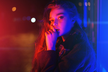 Sexy young woman posing over night city dramatic neon background