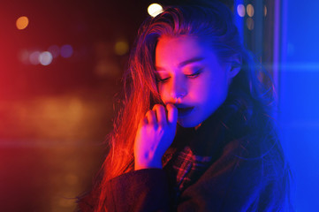 Naklejka premium Sexy young woman posing over night city dramatic neon background