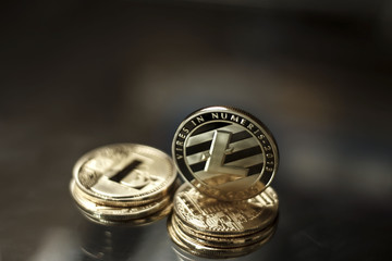 Shining golden litecoin coins on a dark background