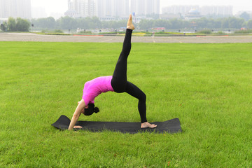 Fototapeta premium Luanan county - September 4, 2016, a woman is doing yoga training in the grass of the park, hebei, China