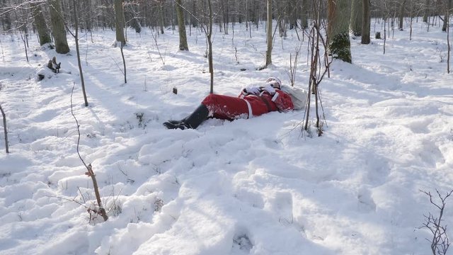 Drunk santa sleeps on snow in the forest.