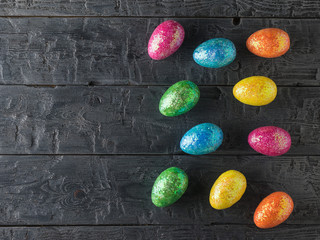 A lot of colorful eggs scattered on a dark rustic table. The decoration of the Easter table. The view from the top.