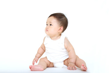 白バックの前に一人座り遊ぶ女の子の赤ちゃん