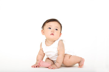 白バックの前に一人座り遊ぶ女の子の赤ちゃん
