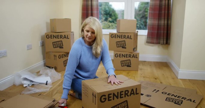 4K Woman taping up cardboard boxes, getting ready for house move. Slow motion.