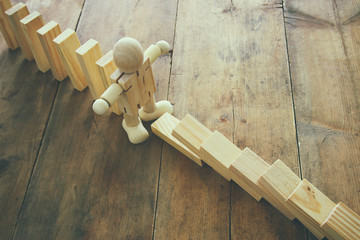 A wooden dummy stopping the domino effect. retro style image executive and risk control concept.