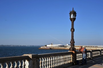 Fishermen are fishing in the harbor of the seaport of Cadiz.