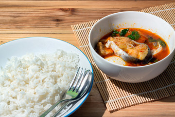 Coconut curry preserved bamboo shoot and Stripped Catfish and rice Thai food on a wooden table.