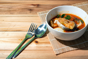Coconut curry preserved bamboo shoot and Stripped Catfish and rice Thai food on a wooden table.