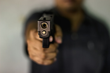 A man holding a gun pointing to a target demonstrates the violence of a gun with blurry background