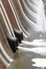 water running down a dam wall and out the outflow pipes at a reservoir