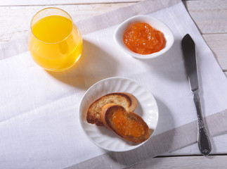 Morning Breakfast set with orange jam on bread toast and juice in glass.