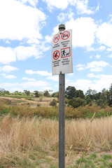 a red, black and white sign of instructions for visitors including Keep Dogs On Lead