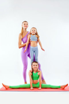 Hatha Yoga Fitness . Young Mother Instructor And Daughters Exercise Gymnastic Together. Isolated On White Background. Family Look.