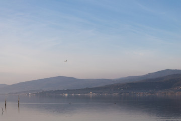 Beautiful view of Trasimeno lake (Umbria, Italy), with hills and blue sky reflecting on water