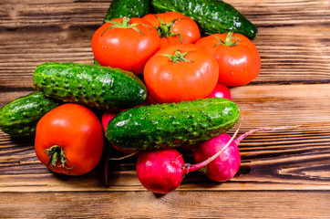 Ripe tomatoes, radish and cucumbers on wooden table. Top view