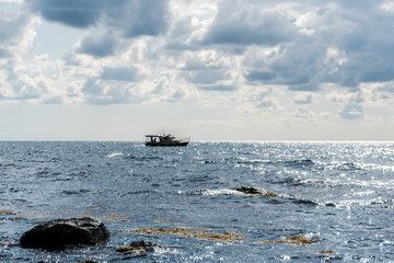 the rocky shore and fishing boat at sea