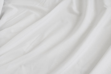 Fototapeta na wymiar Crumpled of bedding sheet background. White fabric material surface.