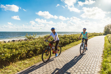 Naklejka premium Women riding bicycles at seaside 