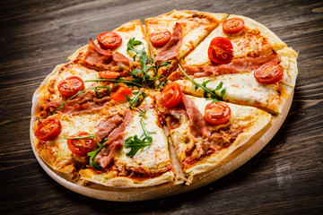 Pizza with ham and vegetables on wooden table