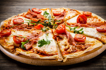 Pizza with ham and vegetables on wooden table