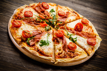Pizza with ham and vegetables on wooden table