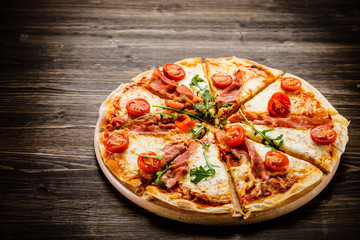 Pizza with ham and vegetables on wooden table