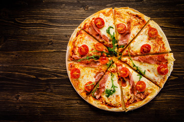 Pizza with ham and vegetables on wooden table