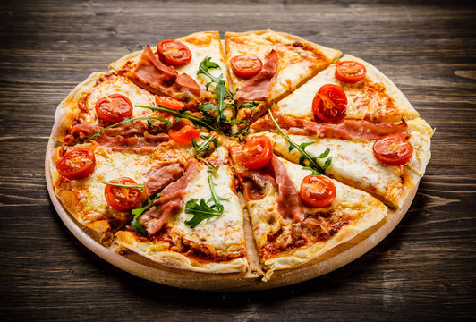 Pizza with ham and vegetables on wooden table