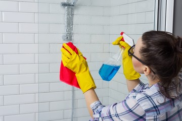 Housework and domestic lifestyle. Woman cleaning bathtub with a cloth