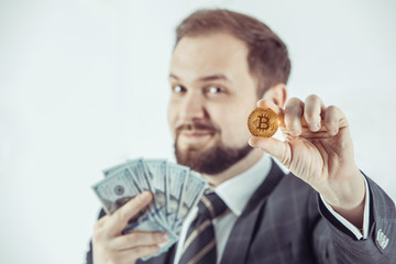 Businessman holding golden Bitcoin, Ticker Symbol BTC and dollar banknotes, focus point on the coin.