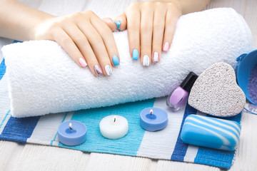 Obraz na płótnie Canvas beautiful colored manicure with candle and towel on the white wooden table.