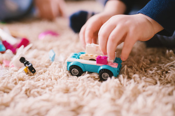 Close up focus view of a plastic toy car on the carpet while little boy hands holding it.