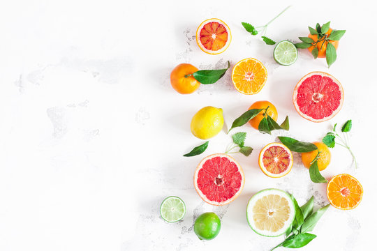 Fruit background. Colorful fresh fruits on white table. Orange, tangerine, lime, lemon, grapefruit. Flat lay, top view, copy space