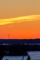 Mountain top bathed in the rays of the sun at sunset overlooking the frozen winter lake from the viewpoint on the mountain top