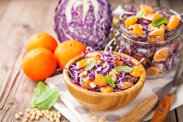 Red cabbage tangerines and pine nuts salad. Selective focus. Copy space.