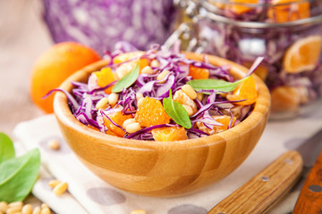 Red cabbage tangerines and pine nuts salad. Selective focus. Copy space.