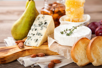 Cheese, honey and fruit on a table. Selective focus. Copy space.