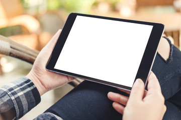 Mockup image of a woman holding black tablet pc with blank white screen with  blur background in cafe