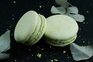 Tasty sweet green macarons cakes on dark background, dark mood