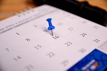 pushpin point to sixteen on calendar on wooden table