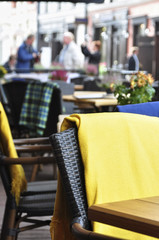 outside patio of an european restaurant - tables and black- brown chairs with yellow blankets for cold weather