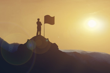 Silhouette of Businessman standing on mountain looking flag on hill at sunset. business target and success concept.