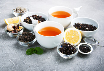 Cups of tea with aromatic dry tea in bowls