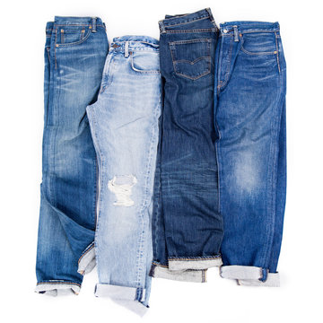 blue jeans in a row isolated on a white background, stack of denim pants, jeans texture, composition