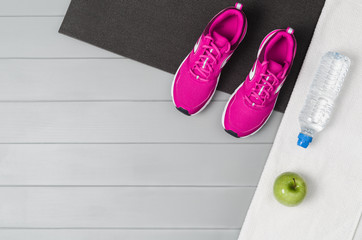 Sport and fitness accessories, healthy and active lifestyle concept on grey wooden floor background with copy space. Products with vibrant, punchy pastel colours. Image taken from above, top view.
