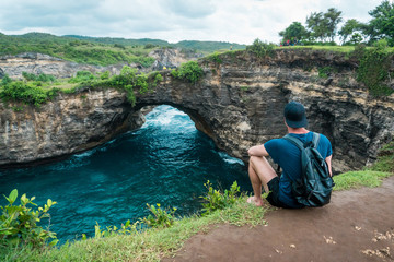 Man sitting on cliff and enjoying beautiful landscape. Broken beach, Nusa Penida