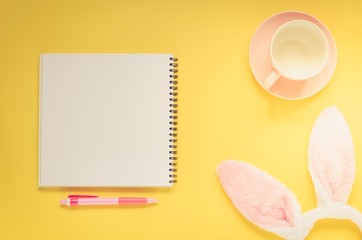 Easter holiday background with notebook and pen, cup for coffee, bunny ears