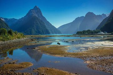 View of Mitre peak at Milford sound, Fiordland national park in south island, New Zealand. Blue sky with reflection of the mountain in the water.